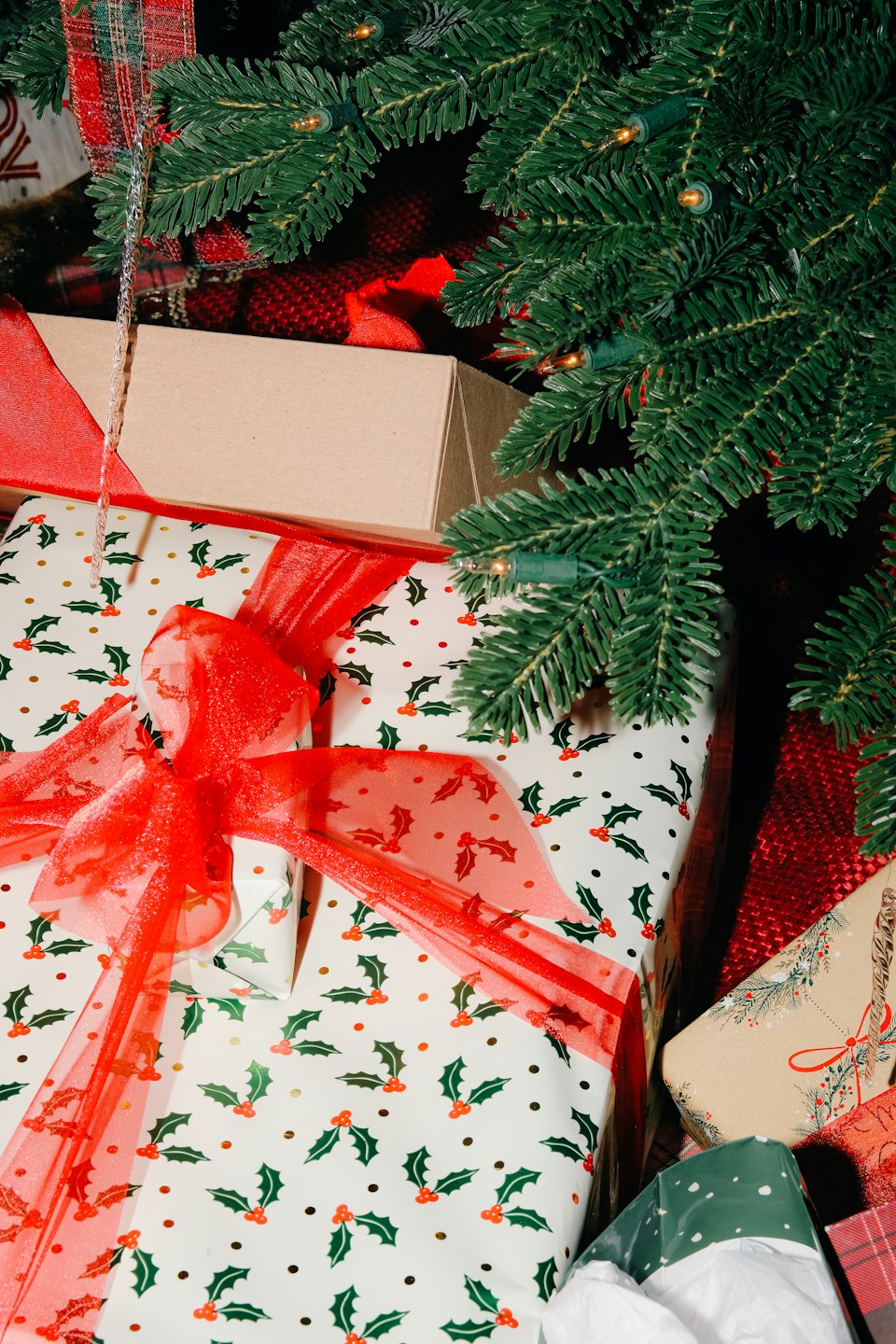 Christmas presents wrapped in festive paper under a lit tree.