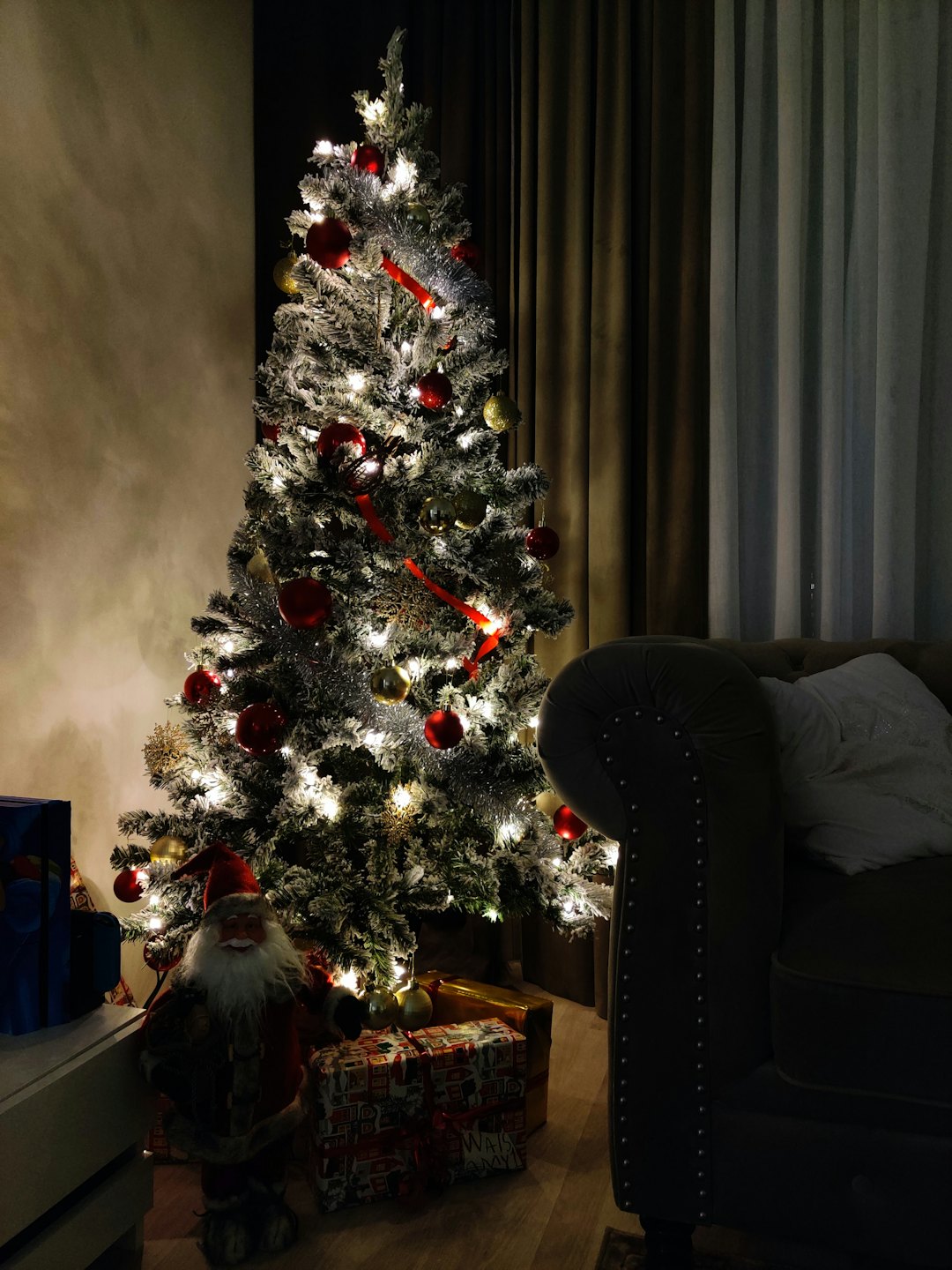 Decorated Christmas tree surrounded by presents in a living room.
