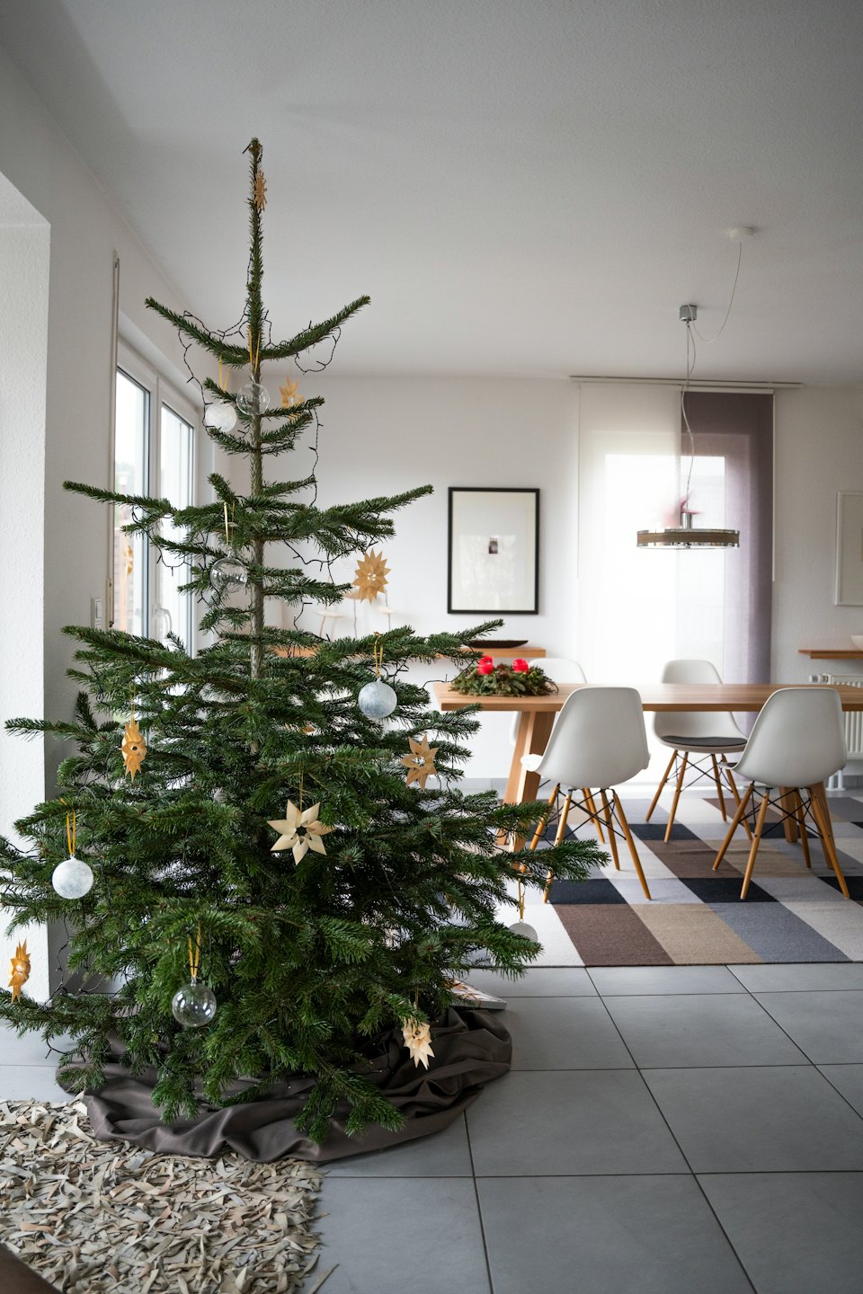 Decorated Christmas tree stands in a modern dining room.